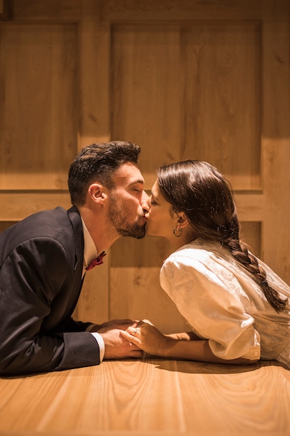 Free photo young woman kissing man lying on floor