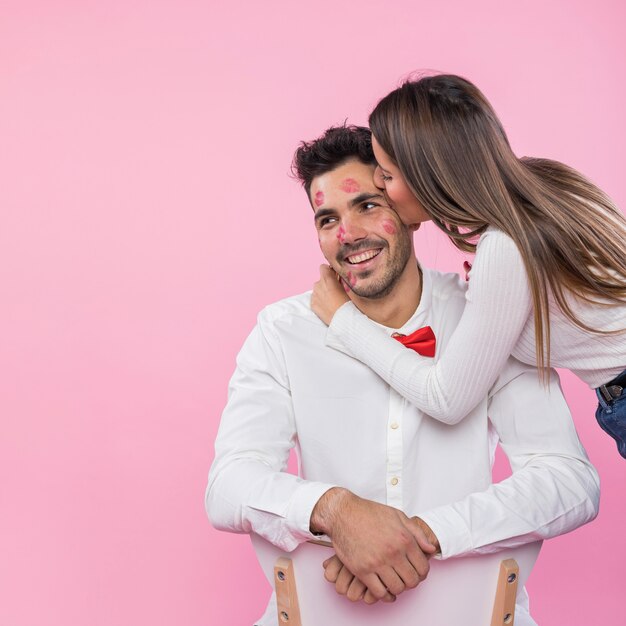 Young woman kissing man with lipstick kiss marks on cheek