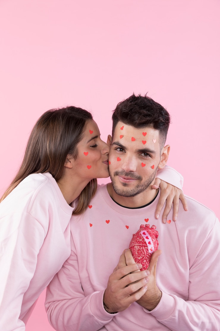 Free Photo young woman kissing smiling man with paper hearts on faces