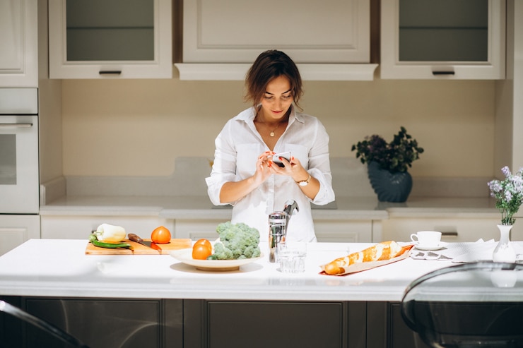 無料Photo 朝食を調理し、電話で話しているキッチンで若い女性