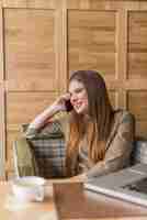 Free photo young woman laughing while talking on the phone