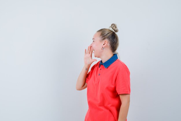 Tシャツで口の近くで手で笑っている若い女性