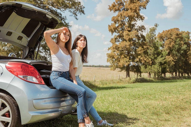 Young woman leaning against their car