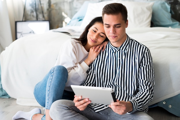 Young woman leaning on boyfriend and watching on tablet