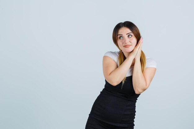 Young woman leaning cheek on palms and looking cute