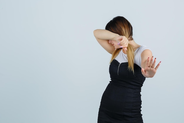 Free photo young woman leaning head on elbow while showing stop gesture