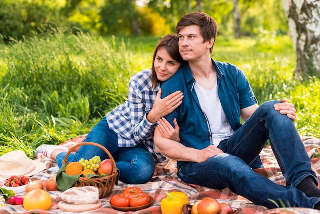 Young woman leaning and hugging boyfriend on blanket