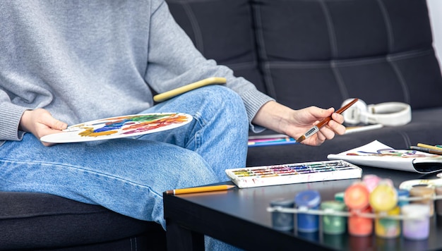 A young woman learns to draw using a video in a smartphone