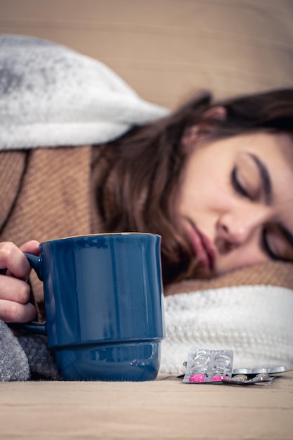 Free photo young woman lies in bed with a cup of drink home treatment colds