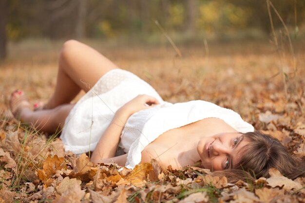 Young woman lies in oak leaves