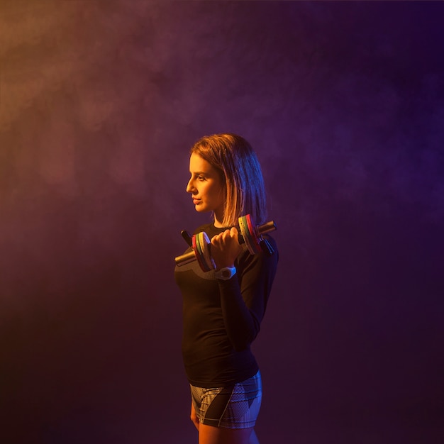 Young woman lifting heavy dumbbell