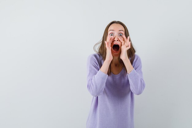 Young woman in lilac blouse shouting for someone and looking troubled 