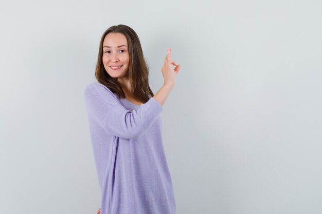 Young woman in lilac blouse showing ok gesture and looking lucky 