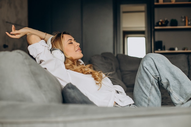 Young woman listening to music in earphones in her appartment