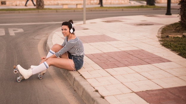 Foto gratuita musica d'ascolto della giovane donna sulla cuffia che si rilassa sulla strada