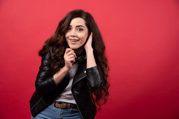 Young woman listening music in headphones and posing on a red background. High quality photo