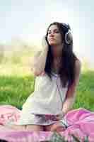 Free photo young woman listening to music on meadow