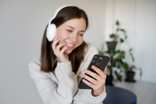 Молодая женщина слушает музыку с помощью своего смартфона и улыбается