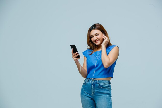 Young woman listening to music with earphones on mobile phone