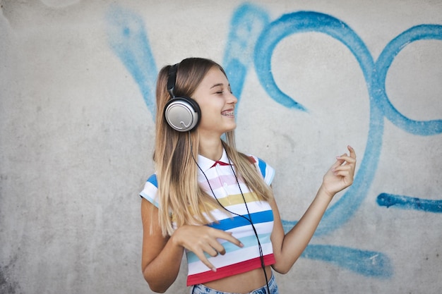 young woman listens to music on a background with graffiti