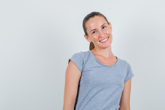 Young woman looking away while smiling in grey t-shirt , front view.