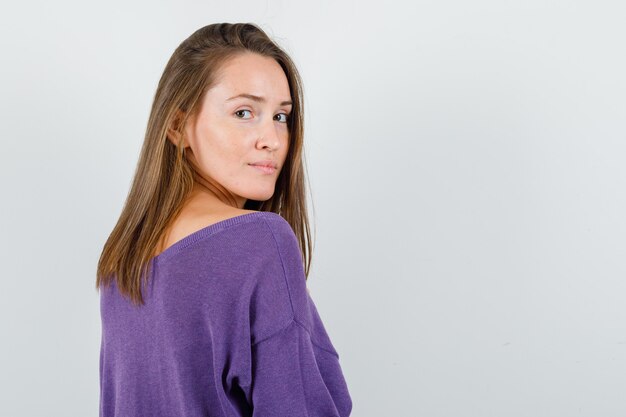 Young woman looking back in violet shirt and looking sensible , back view.