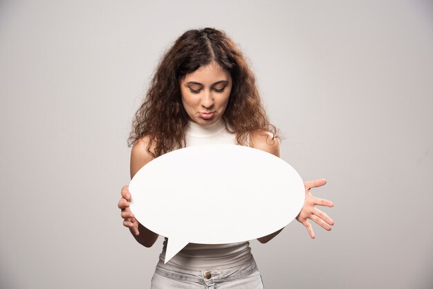 Young woman looking at blank white speech bubble. High quality photo