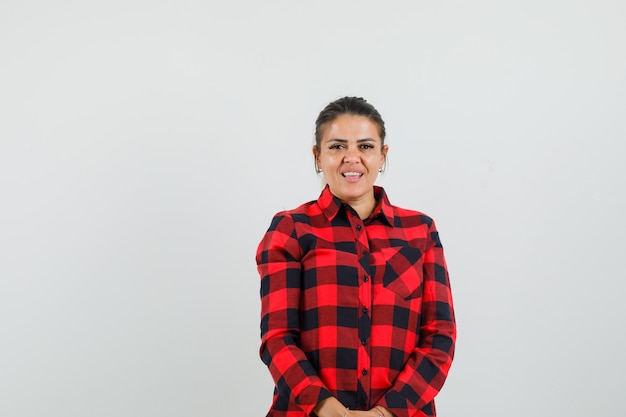 Free photo young woman looking at camera in checked shirt and looking cheery. front view.