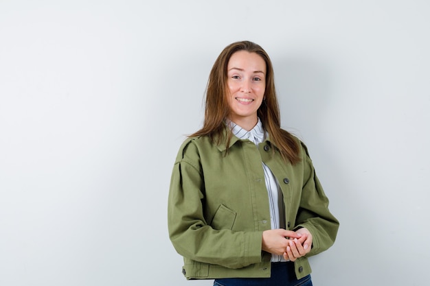 Young woman looking at camera in shirt, jacket and looking cheerful, front view.