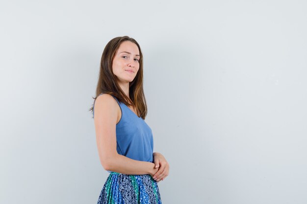 Young woman looking at camera in singlet, skirt and looking confident. front view.