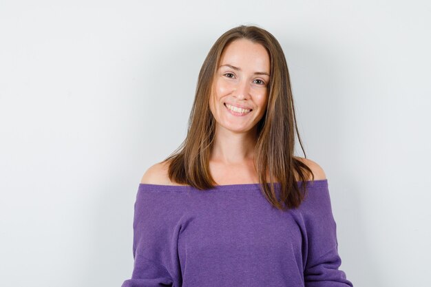 Young woman looking at camera in violet shirt and looking glad. front view.