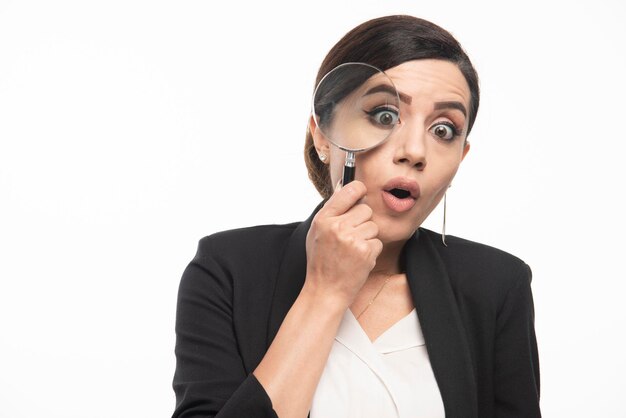 Young woman looking at camera with magnifying glass. High quality photo