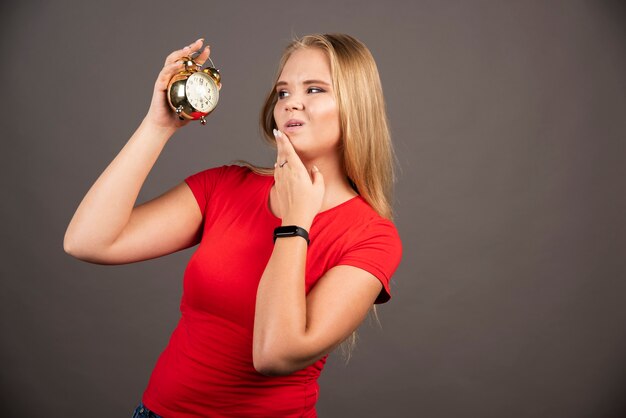 Young woman looking at clock with exhausted expression.