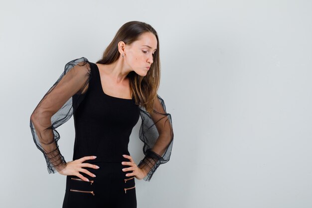 Young woman looking down carefully in black blouse and looking focused. front view. space for text