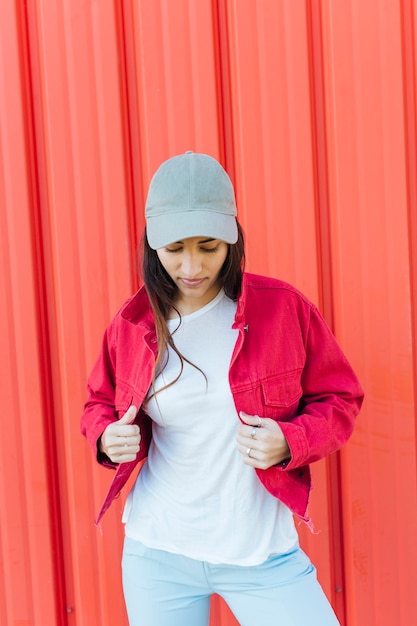金属製の背景に対して赤いジャケット立って保持しながら見下ろしている若い女性