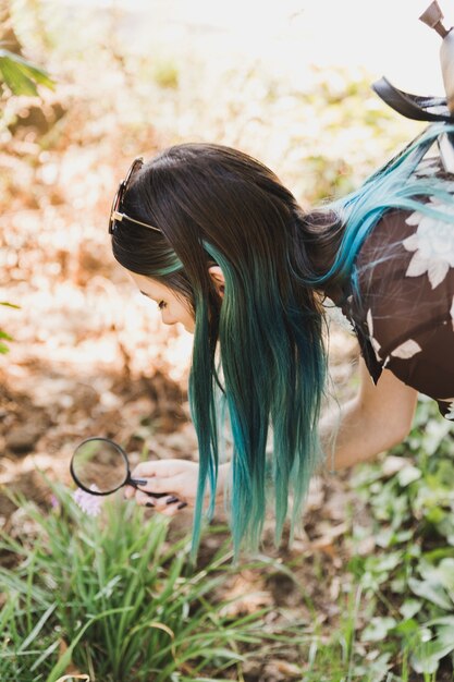 Young woman looking flowers through magnifying glass