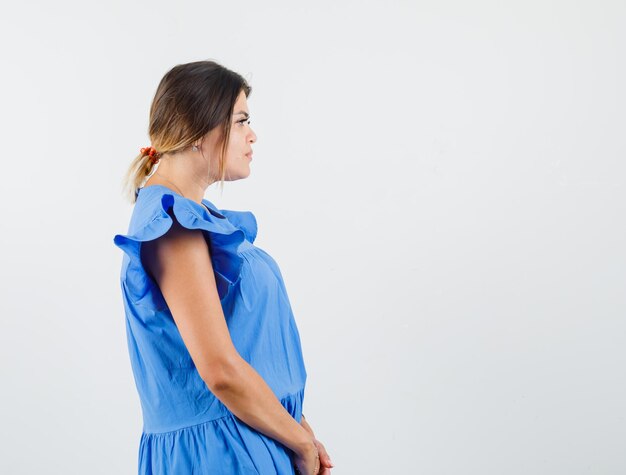 Young woman looking at front of her in blue dress and looking focused 