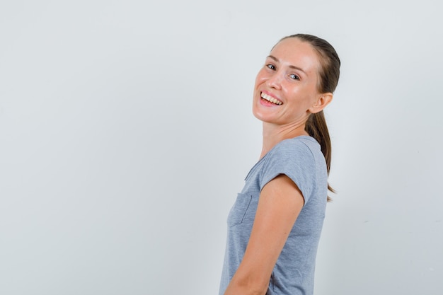 Young woman looking in grey t-shirt and looking cheerful .