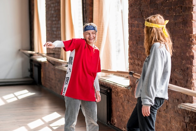 Free photo young woman looking at her female friend dancing in the class