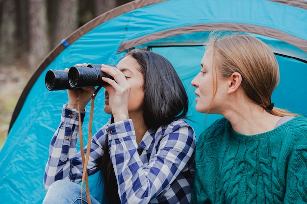 Free photo young woman looking at her friend while using binoculars