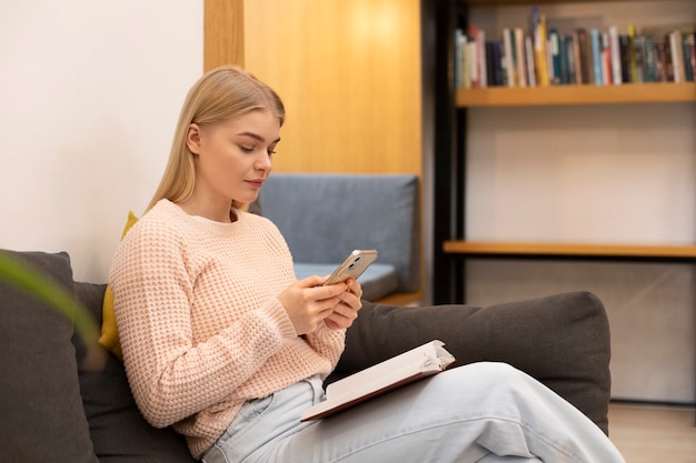 Young woman looking at her smartphone in a library