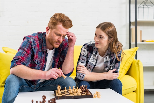 Free photo young woman looking at her thoughtful boyfriend playing the chess