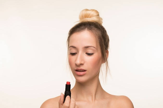 Young woman looking at lipstick 