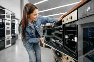 Free photo young woman looking for new electric oven in a shopping mall