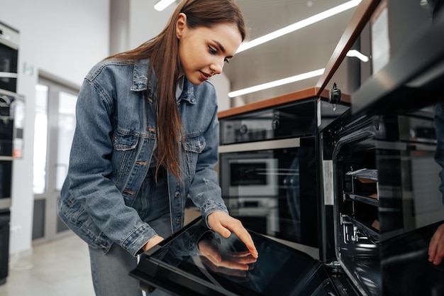 Young woman looking for new electric oven in a shopping mall