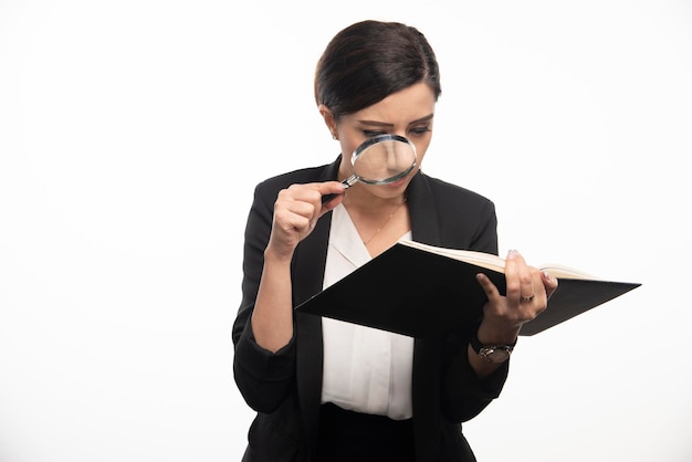 Young woman looking at notebook with magnifying glass. High quality photo