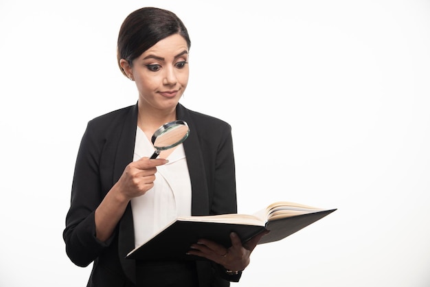 Young woman looking at notebook with magnifying glass. High quality photo