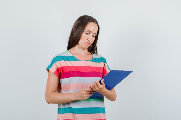 Tシャツ、正面図でクリップボードのメモを見ている若い女性。