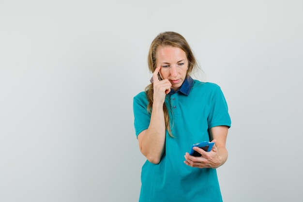 Young woman looking over notes on clipboard in t-shirt and looking hesitant. 