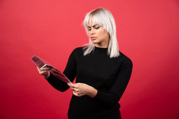 Young woman looking on a photo tape on a red background . High quality photo